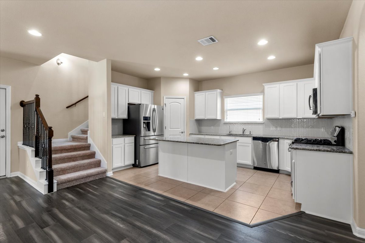 3451 Mayfield Ranch Boulevard, Unit 311 Round Rock, TX 78681 - Photo 8 of 40 Open-concept kitchen featuring white cabinetry, stainless steel appliances, a central island, recessed lighting, and a subway tile backsplash