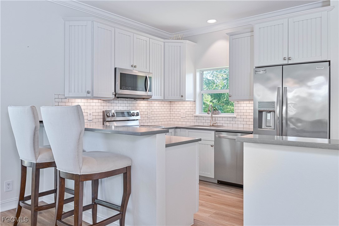 6941 Hunters Road Naples, FL 34109 - Photo 32 of 45 a kitchen with stainless steel appliances granite countertop white cabinets a window and a refrigerator