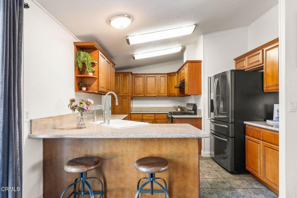 1025 Cachuma Avenue, Unit 59 Ventura, CA 93004 - Photo 6 of 36 a kitchen with stainless steel appliances granite countertop a refrigerator a sink a stove a dining table and chairs with wooden floor