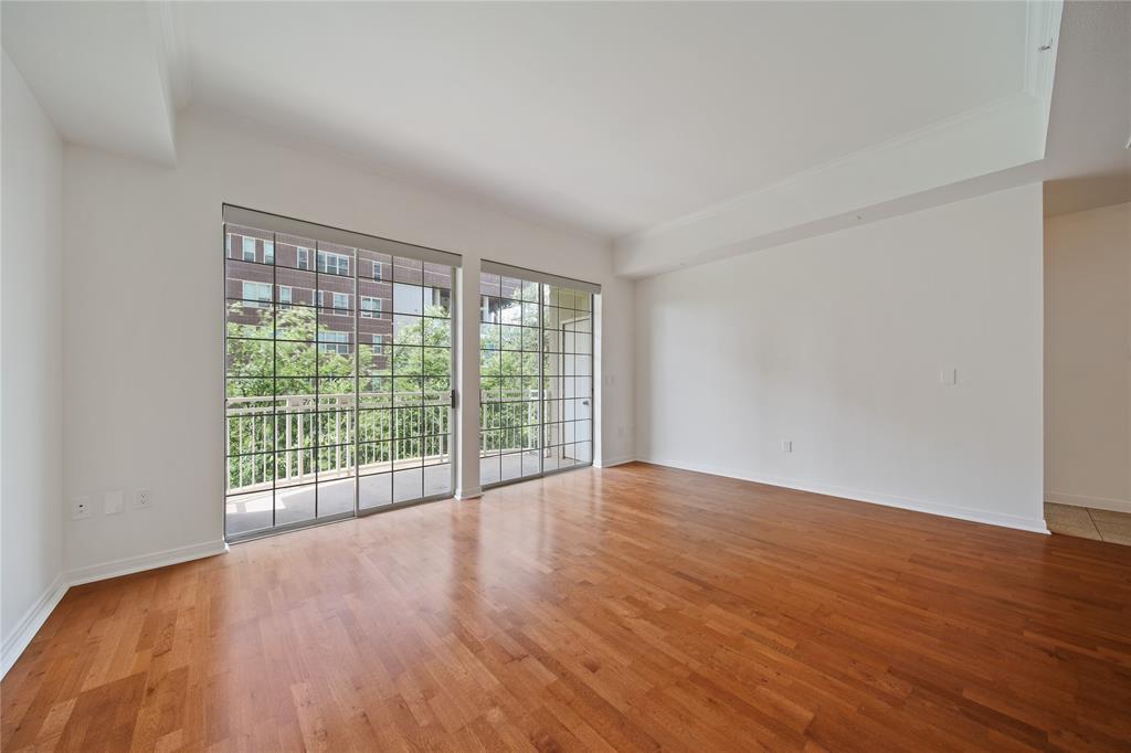 3225 Turtle Creek Boulevard, Unit 320 Dallas, TX 75219 - Photo 8 of 24 a view of an empty room with wooden floor and a window