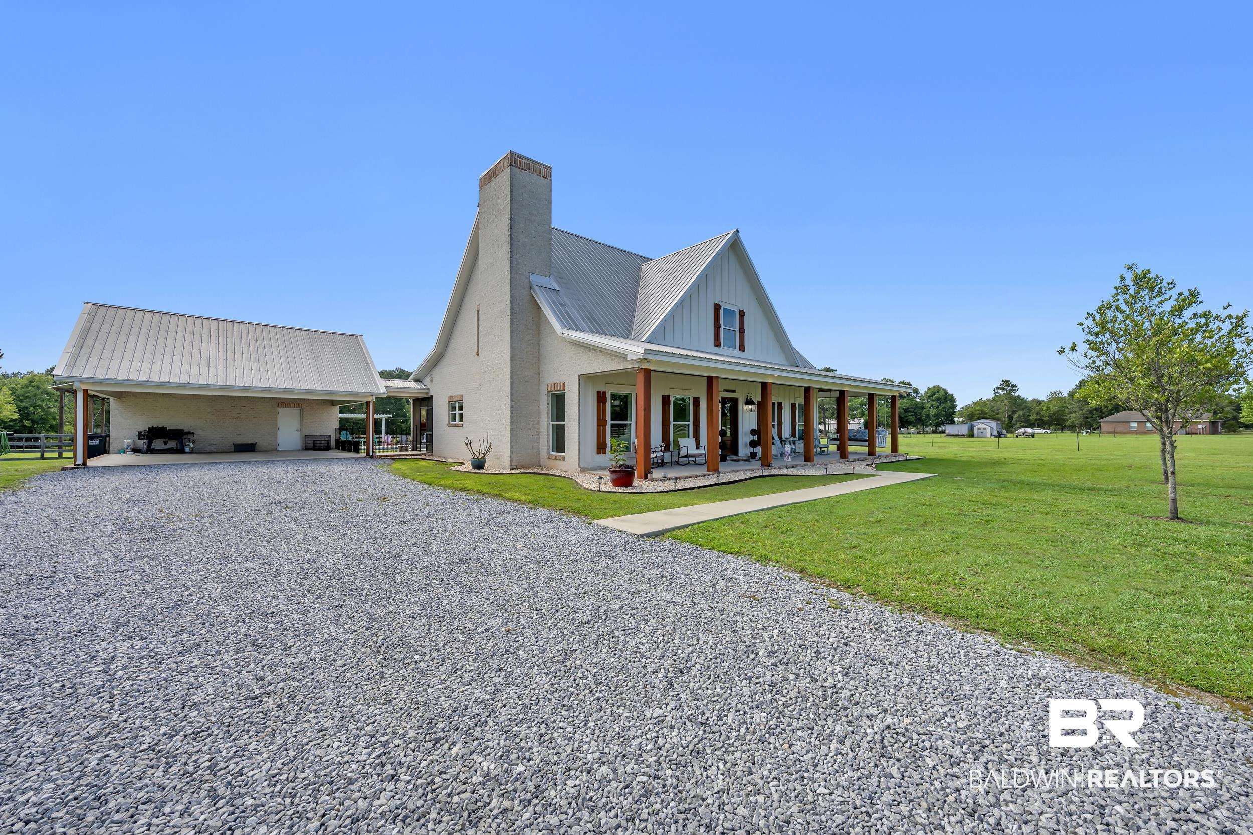6576 Ranch Loop Road East Grand Bay, AL 36541 - Photo 6 of 39 White brick residence featuring a metal roof, prominent chimney, and a full-length covered porch with wood columns