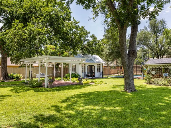 a view of a tennis ground with large trees