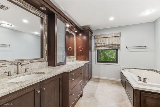 a bathroom with a granite countertop double vanity sink and a bathtub