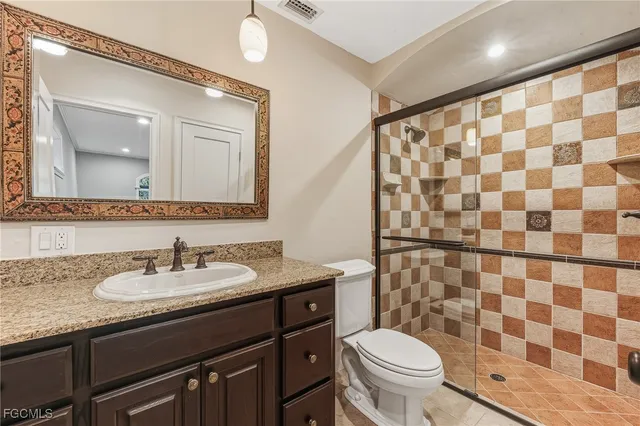 a bathroom with a granite countertop sink a toilet and a mirror