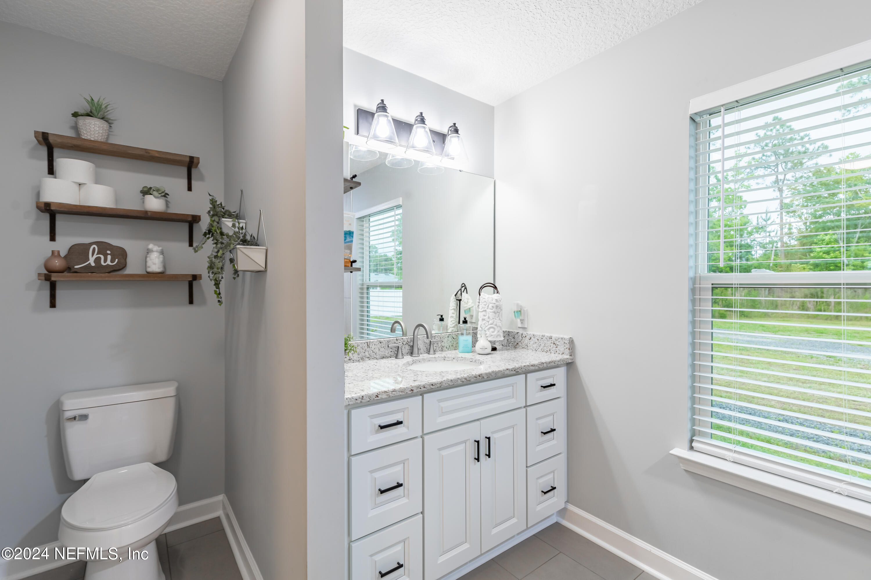 6477 Keith Griffis Circle Macclenny, FL 32063 - Photo 24 of 30 a spacious bathroom with a toilet sink and mirror