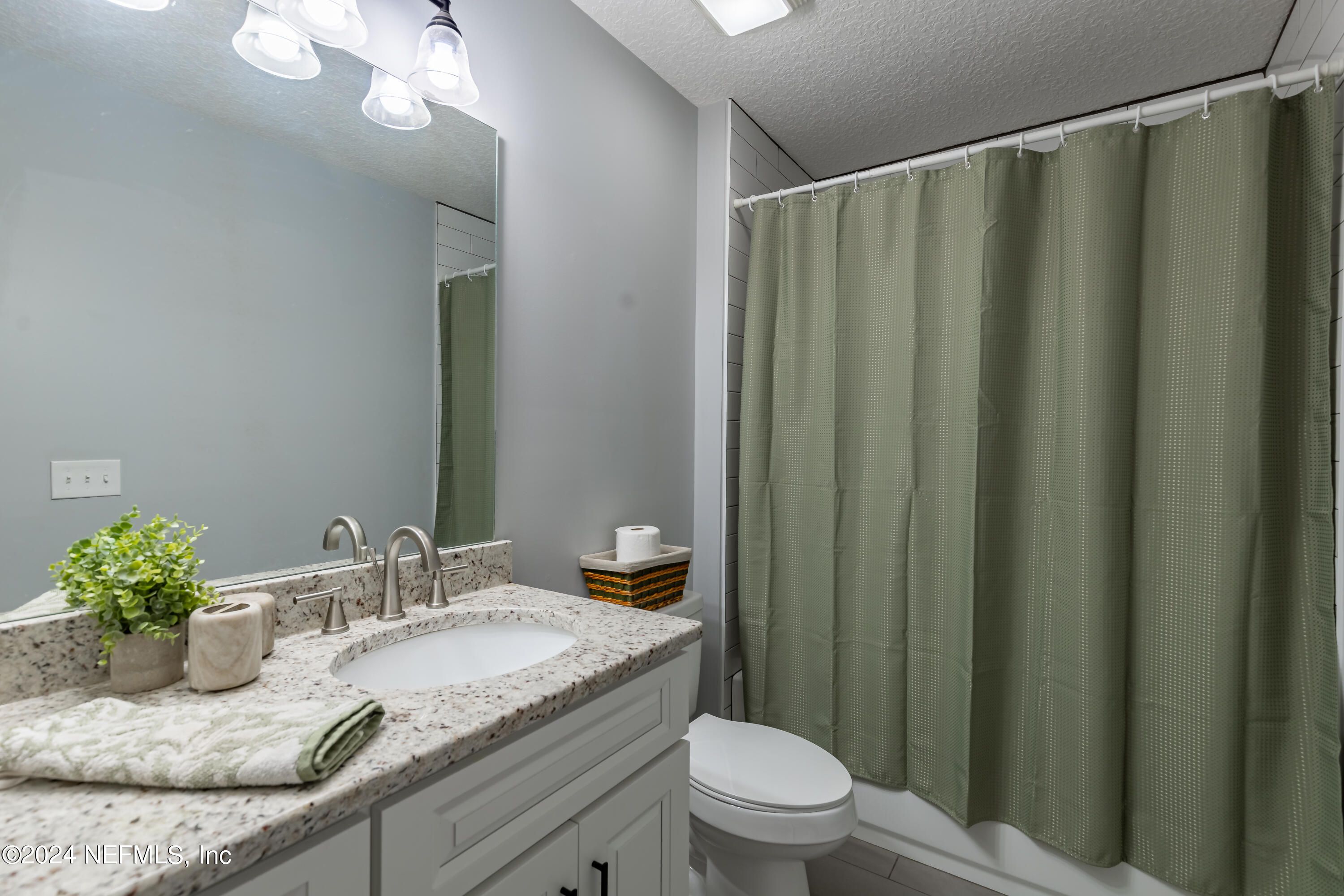 6477 Keith Griffis Circle Macclenny, FL 32063 - Photo 28 of 30 a bathroom with a granite countertop sink and a mirror