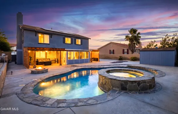 a view of a swimming pool with a lounge chairs in front of a house
