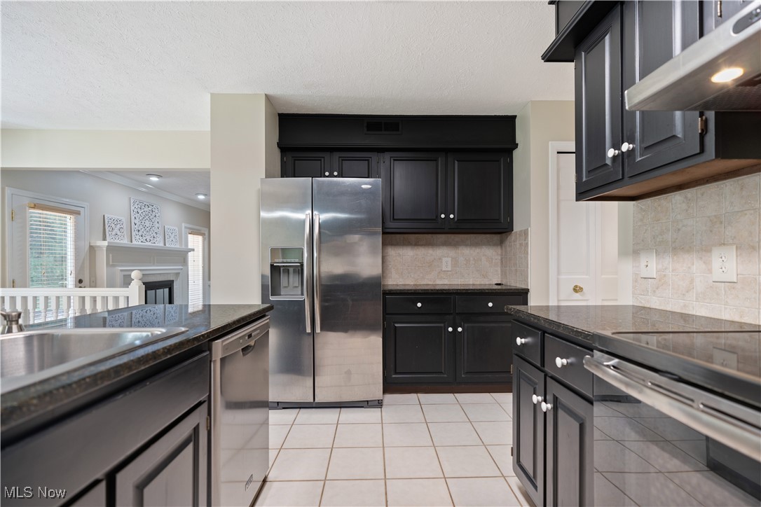 3960 Bramshaw Road Northwest Canton, OH 44718 - Photo 13 of 33 Kitchen with dark stone countertops, backsplash, light tile patterned floors, stainless steel appliances, and ornamental molding