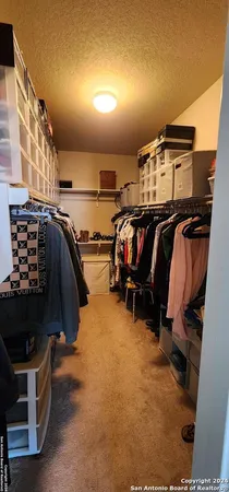 a view of walk in closet with clothes and shoes