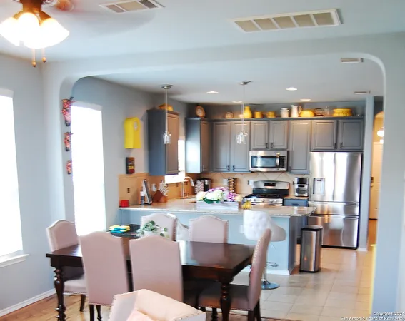 a dining room with stainless steel appliances a dining table chairs and a refrigerator