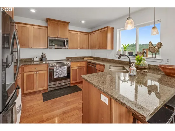 a kitchen with stainless steel appliances granite countertop a sink a stove and a wooden floors