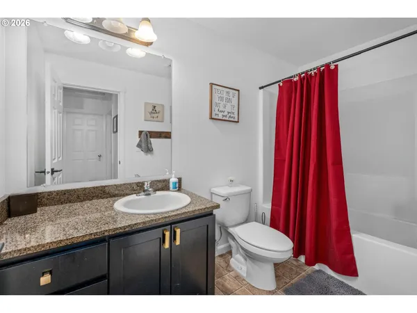 a bathroom with a granite countertop sink a toilet a mirror and shower curtain
