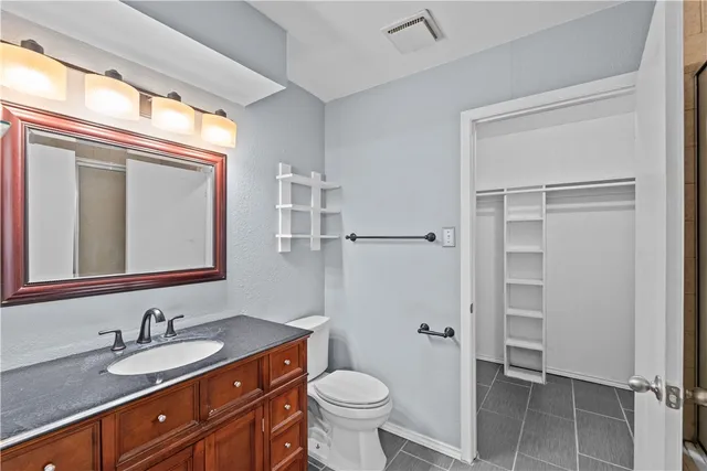 a bathroom with a granite countertop toilet sink and mirror