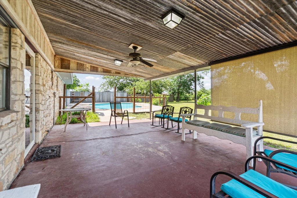 2421 Post Oak Road Webberville, TX 78653 - Photo 25 of 36 The covered patio features a rustic corrugated metal ceiling with a ceiling fan to keep things cool, a built-in sunshade, and a huge concrete deck. You can sit out here in the shade and look right out at the pool.