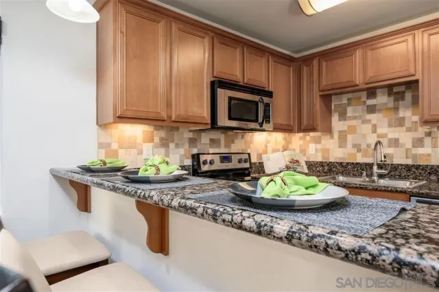 a kitchen with stainless steel appliances granite countertop a stove a sink and a microwave