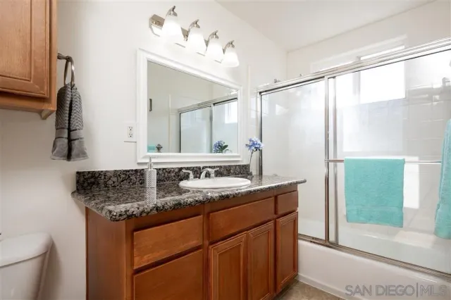a bathroom with a granite countertop sink and a mirror
