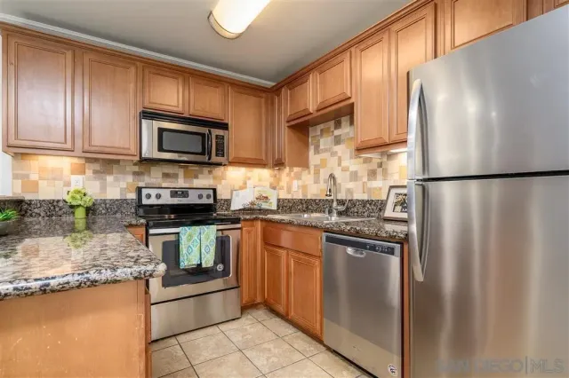 a kitchen with granite countertop a refrigerator stove and microwave