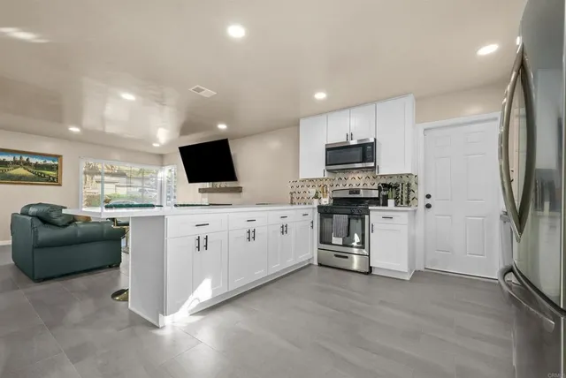 a kitchen with microwave a refrigerator and a stove top oven