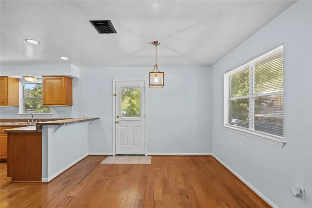 a view of an empty room with window and wooden floor