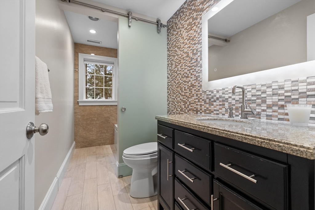 9 Augustus Road Lexington, MA 02421 - Photo 18 of 41 a bathroom with a granite countertop sink a toilet a mirror and shower