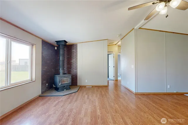 a view of empty room with wooden floor and fan