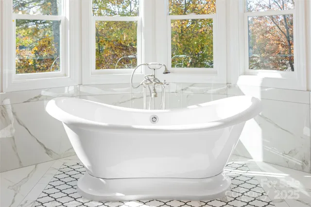 a white bath tub sitting in a bathroom next to a window