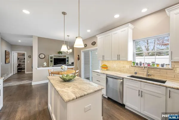 a kitchen with stainless steel appliances granite countertop a sink a stove and a wooden floors