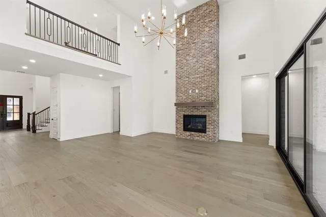 a view of an empty room with chandelier fan and a fireplace