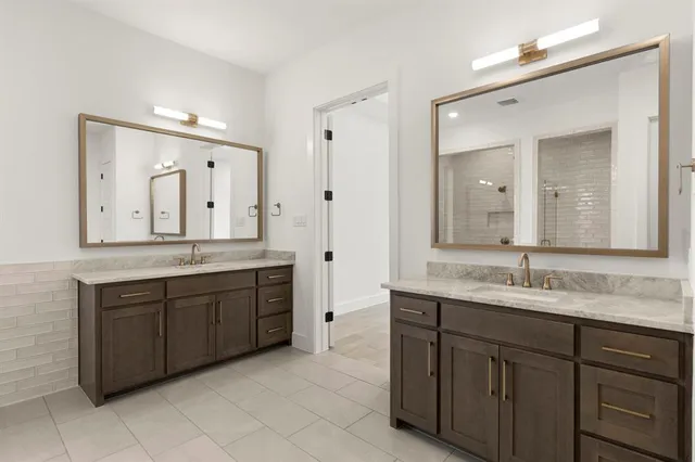 a bathroom with a granite countertop double vanity sink and a mirror