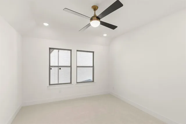 an empty room with chandelier fan and windows