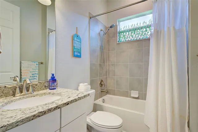 a bathroom with a granite countertop sink a toilet and shower
