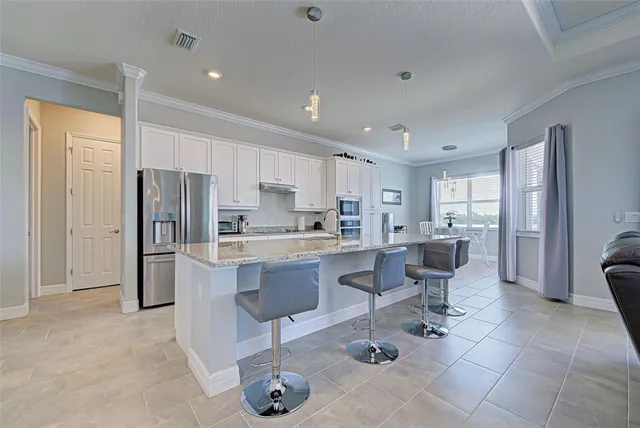 a kitchen with stainless steel appliances kitchen island granite countertop a refrigerator and cabinets