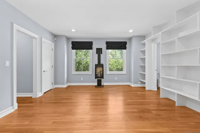 a view of an empty room with a window and wooden floor