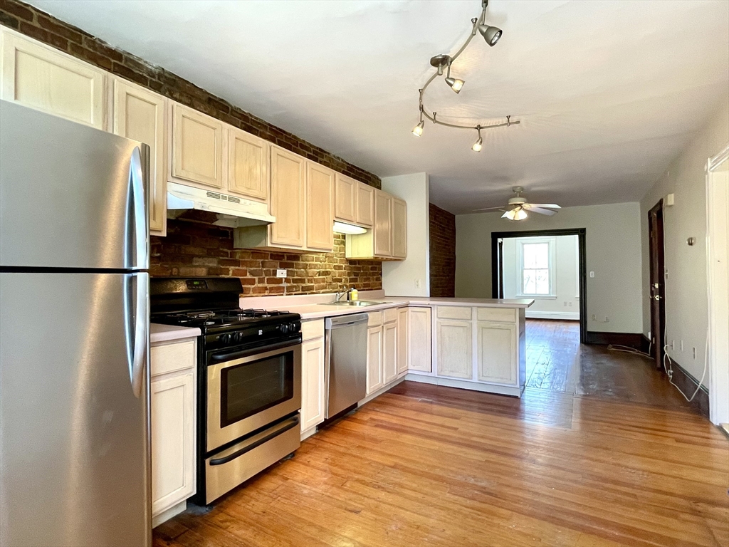 a kitchen with stainless steel appliances granite countertop a refrigerator a sink dishwasher a stove and white countertops with wooden floor