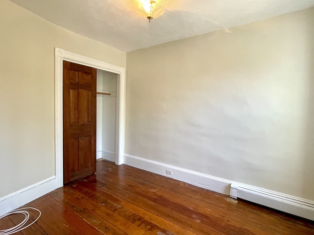 6 Mead Street, Unit 2 Boston, MA 02134 - Photo 2 of 8 an empty room with wooden floor and closet
