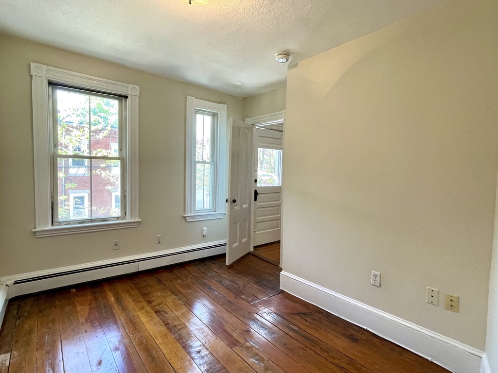 6 Mead Street, Unit 2 Boston, MA 02134 - Photo 3 of 8 an empty room with wooden floor and windows