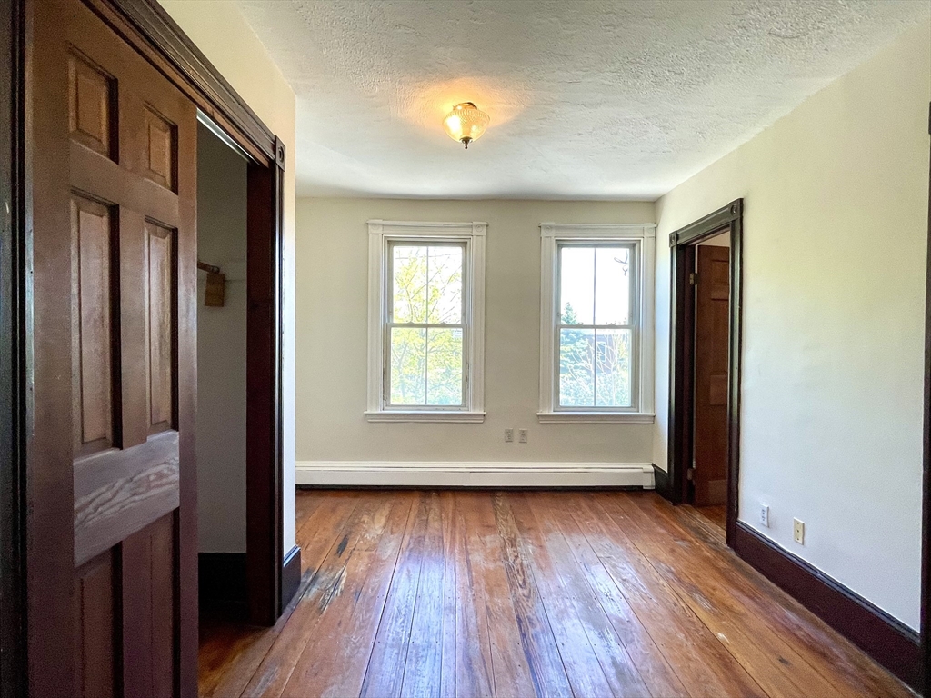 6 Mead Street, Unit 2 Boston, MA 02134 - Photo 6 of 8 an empty room with wooden floor and windows