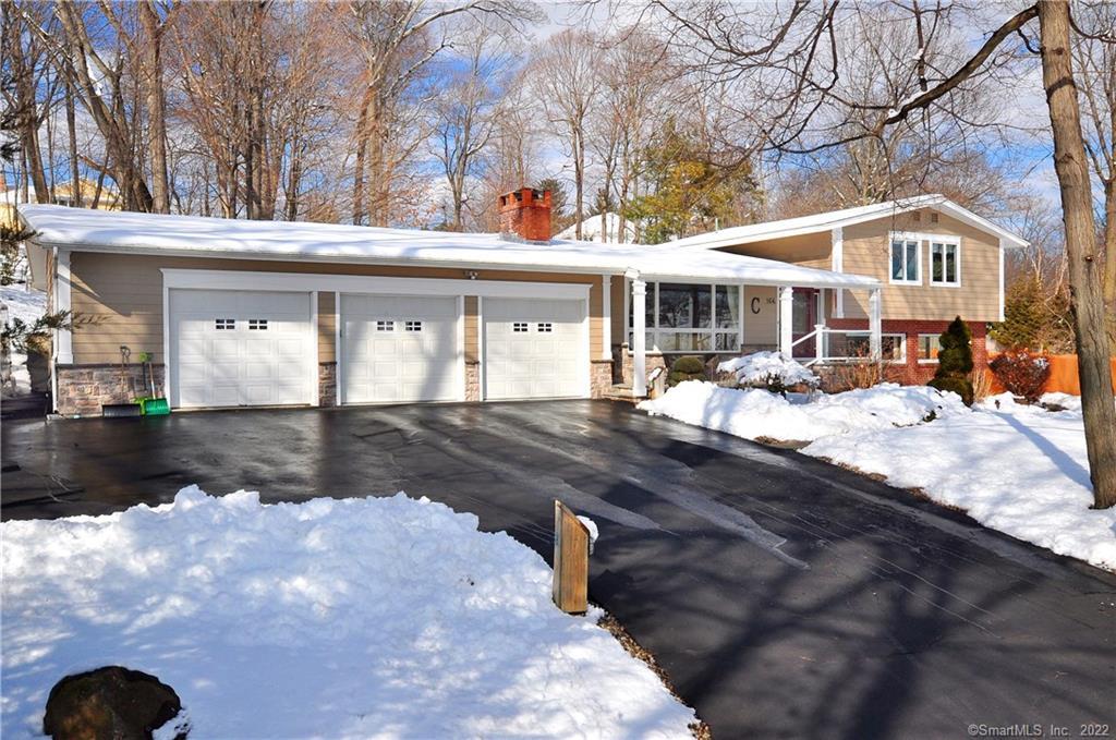 a front view of a house with a yard outdoor seating and covered with trees