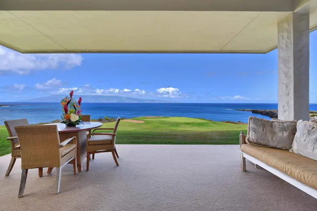 a view of a chairs and table in the patio next to a yard