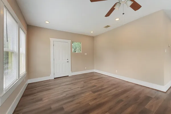 an empty room with wooden floor cabinet and windows