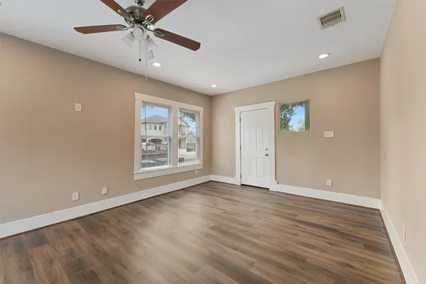 a view of an empty room with a window and wooden floor