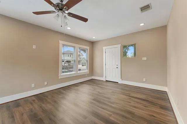 a view of an empty room with a window and wooden floor