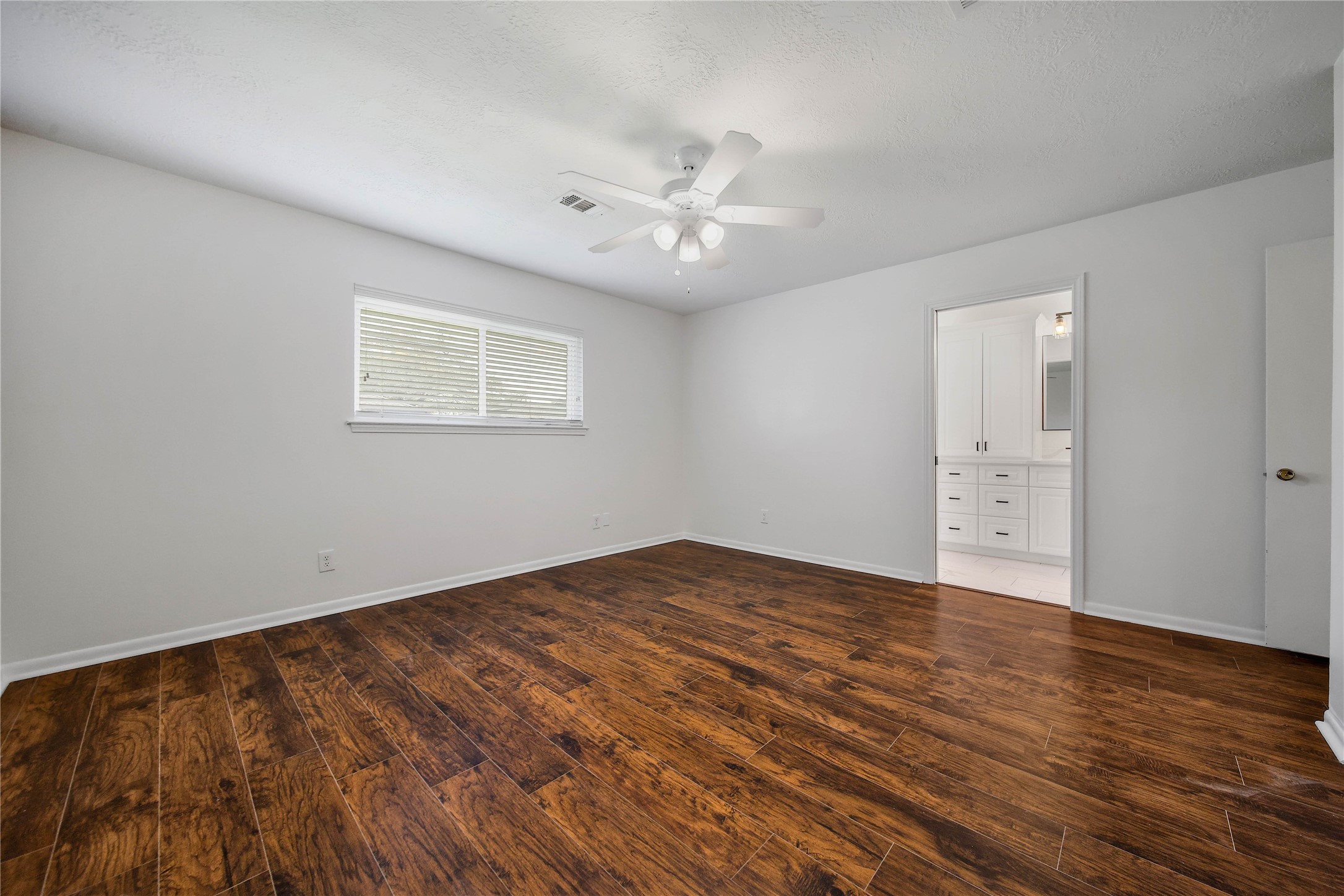 955 Thornton Road Houston, TX 77018 - Photo 15 of 27 Bright primary bedroom with fresh luxury vinyl plank flooring that offers a handscraped wood effect, paired with a beautifully remodeled ensuite bath completed in 2026.
