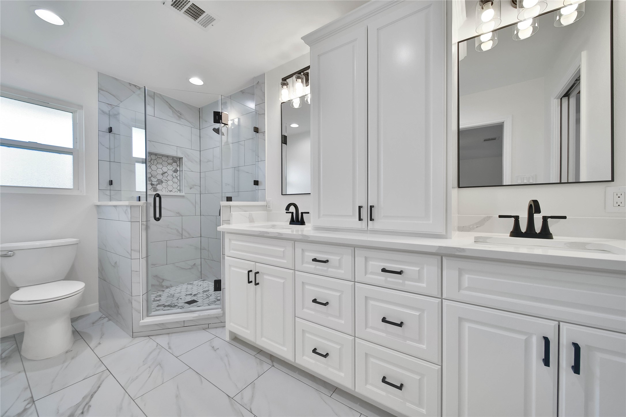 955 Thornton Road Houston, TX 77018 - Photo 17 of 27 Freshly remodeled in 2026, the primary bath offers a clean, modern design with upgraded tilework, a double vanity, and a glass-enclosed shower.