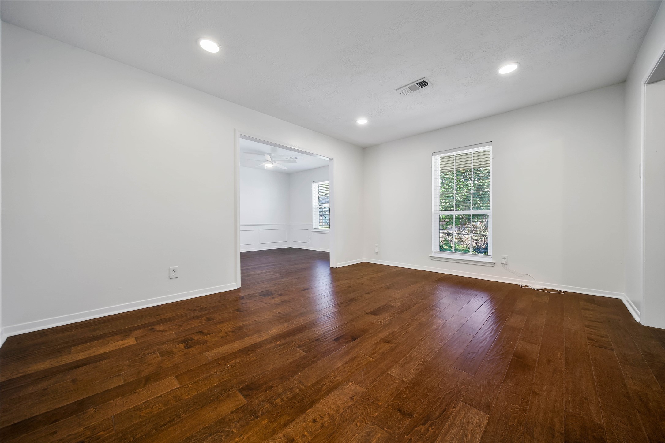 955 Thornton Road Houston, TX 77018 - Photo 4 of 27 A view from the living room into the dining room shows how each space has its own window, bringing in great natural light throughout the day. The rich engineered wood floors add warmth and durability, making the space both inviting and easy to maintain.