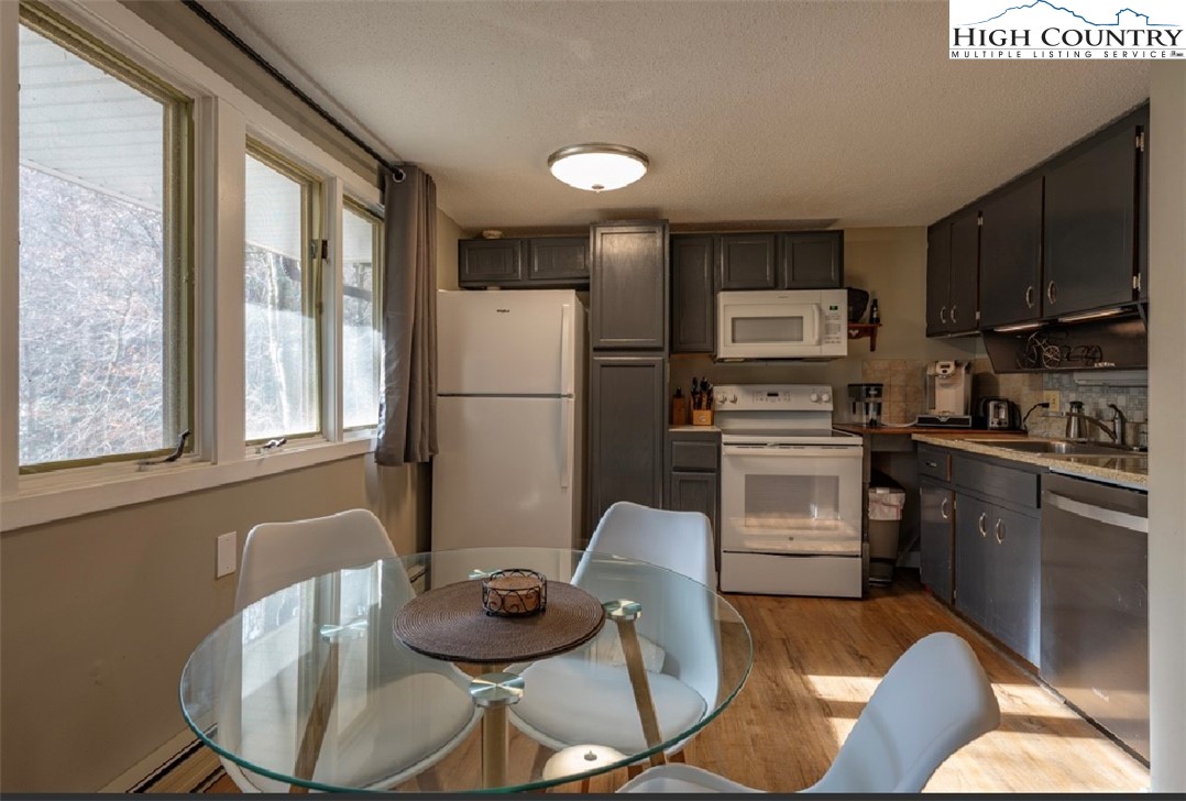 165 Briarcliff Road, Unit J42 Banner Elk, NC 28604 - Photo 7 of 20 a kitchen with stainless steel appliances granite countertop a refrigerator a stove a sink dishwasher a dining table and chairs with wooden floor