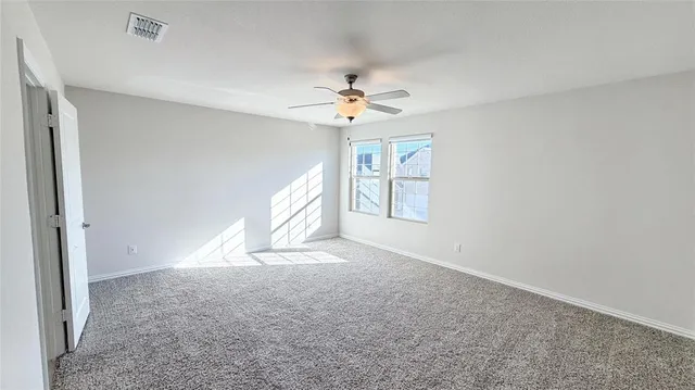 an empty room with windows and ceiling fan