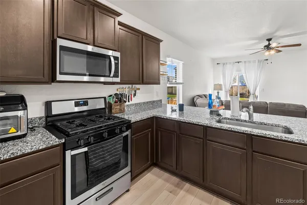 a kitchen with granite countertop a sink dishwasher stove and microwave with wooden cabinets