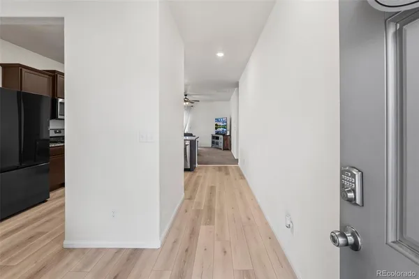 a view of a hallway with wooden floor and a bathroom