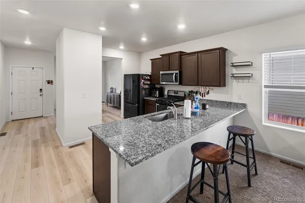 a kitchen with stainless steel appliances granite countertop a stove refrigerator and a wooden cabinets